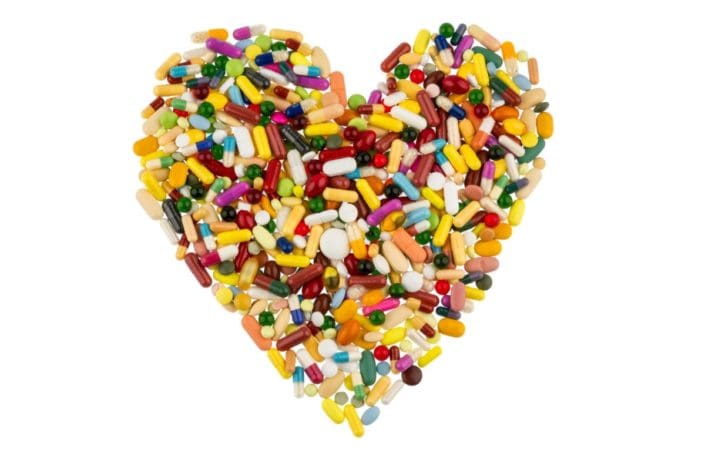 Colorful tablets and capsules arranged in heart shape to represent medicine for heart problems