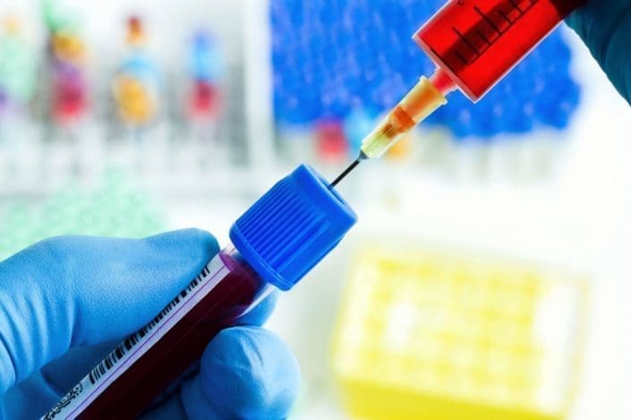 A syringe injecting blood into a tube