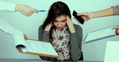 Woman holding head, showing stress while many things are being handed to her