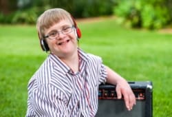 Close up portrait of young man with down syndrome wearing headphones outdoors