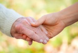 a senior holding hands with a caregiver