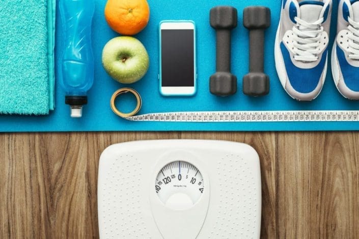 Collection of the tools you need to lose weight, including water, healthy snacks, fitness equipment, and a scale
