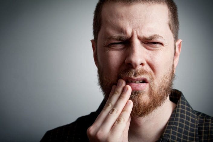 Close-up of man holding his mouth in pain