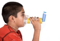 young boy using spacer and mask with asthma inhaler