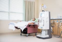 Young male patient sleeping in hospital bed while receiving dialysis treatment