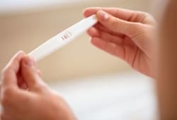 close-up of a woman’s hands holding a positive pregnancy test
