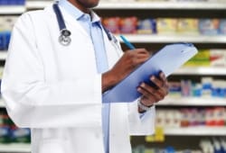 doctor writes on clipboard in front of aisle of OTC medicines