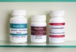 Bottles of otc pain relievers including ibuprofen, aspirin, and acetaminophen in a medicine cabinet