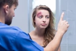 A woman with a head injury being checked by a doctor