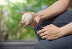 close-up of a young man in jeans holding a baseball in his hand