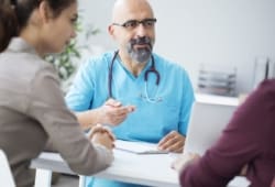 Two people talking to a doctor in the doctor’s office