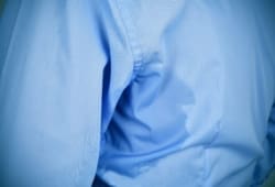 closeup of a man wearing a blue shirt with an underarm sweat stain