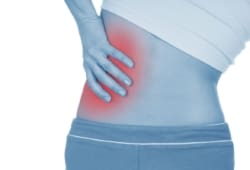 A woman holding her lower back on one side, indicating kidney pain