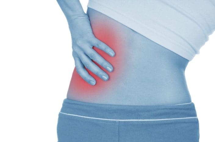A woman holding her lower back on one side, indicating kidney pain