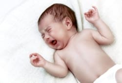 newborn baby crying in white bed