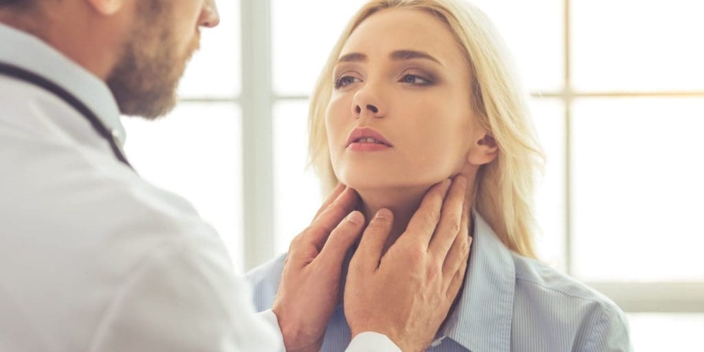 doctor examining female patient for hypothyroidism while working in his office