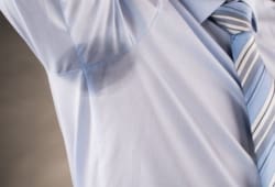 Close up of a man wearing a dress shirt with sweat stains in the armpit