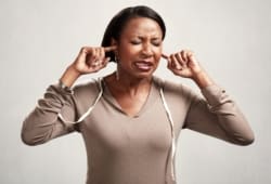 A woman grimaces while putting her fingers in her ears. Tinnitus causes you to hear an “internal” noise in one ear or both ears. You may hear the noise constantly, or it may come and go.