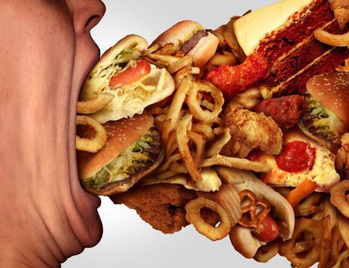 Person’s mouth consuming fast food, junk food, and baked goods, which contain bad trans fats.