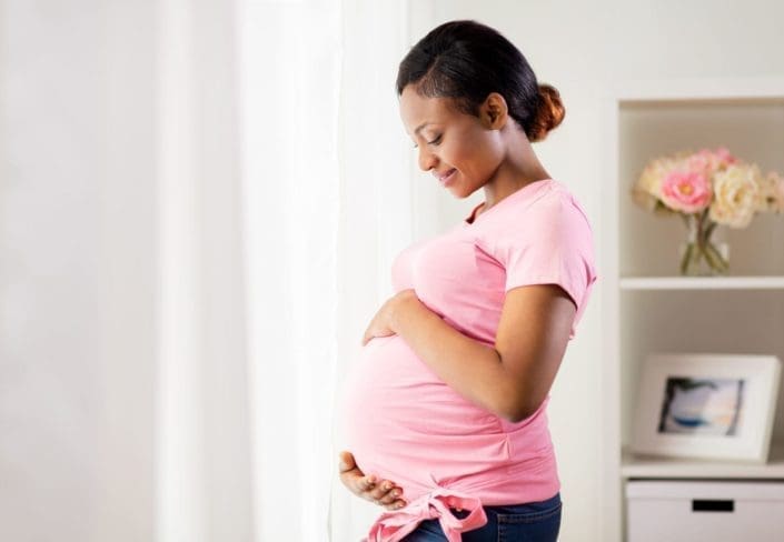 A happy pregnant woman holding her pregnant belly