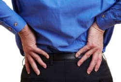 A businessman holds his hands on his aching hips. Bursitis of the hip is the swelling of the bursae, fluid-filled sacs that cushion tendons, ligaments, and muscles. It can cause pain and tenderness.