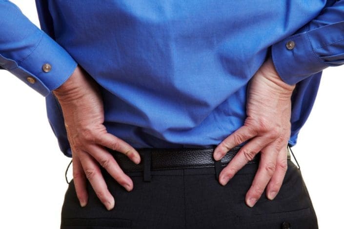 A businessman holds his hands on his aching hips. Bursitis of the hip is the swelling of the bursae, fluid-filled sacs that cushion tendons, ligaments, and muscles. It can cause pain and tenderness.