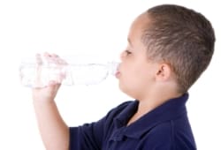 Boy drinking from water bottle on white background