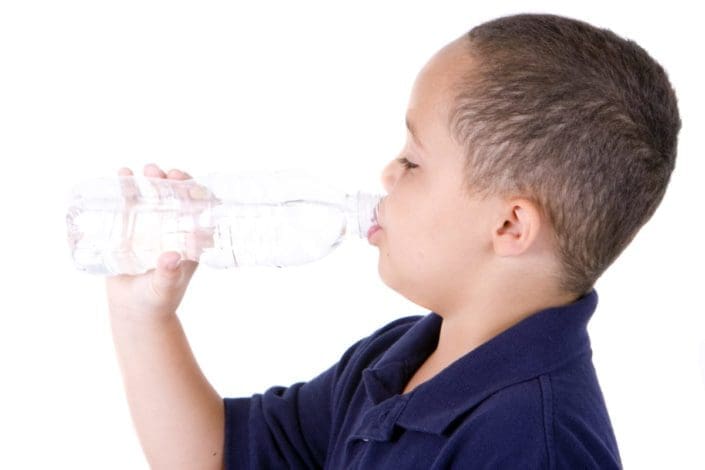 Boy drinking from water bottle on white background