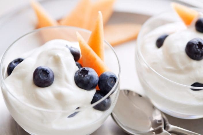 A photo of creamy yogurt sprinkled with blueberries and cantaloupe