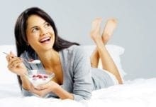Woman smiling and eating yogurt with berries