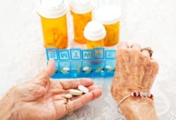 Closeup of elderly woman’s hands sorting several prescriptions
