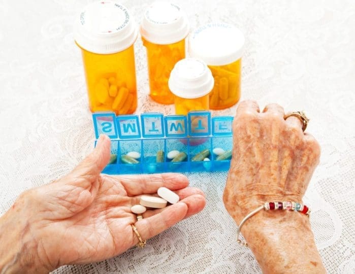 Closeup of elderly woman’s hands sorting several prescriptions