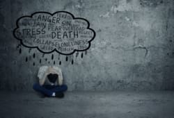 Depressed teenage boy sitting alone with word cloud describing symptoms of depression