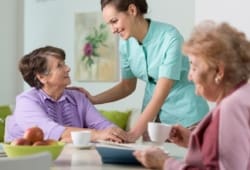 Two older women visiting with nurse in nursing home