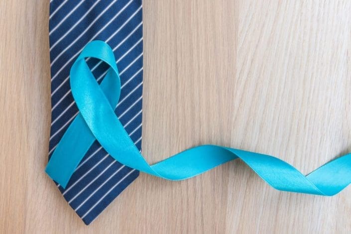 Light blue ribbon and navy blue and white striped tie on wood