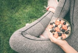 Athlete sitting and holding a bowl of oatmeal and berries in lap