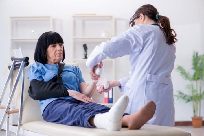 Doctor treating a senior woman who has possible bone fractures