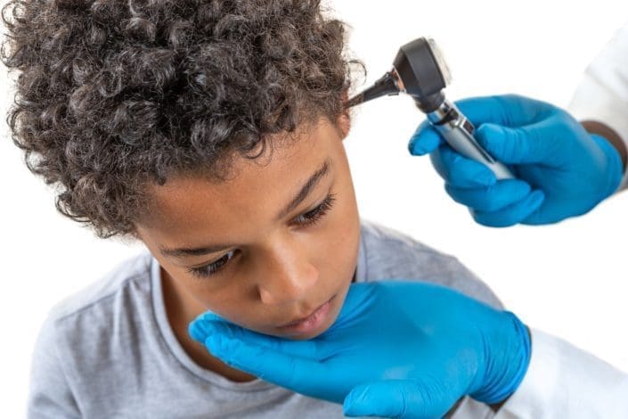 A doctor examines the ear of a boy suffering from eustachian tube dysfunction.