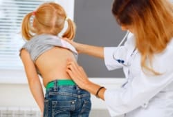 Pediatrician examining little girl with back problems.