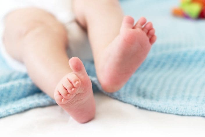 A baby lays on a blue blanket with his legs and feet visible. Rickets is a rare disorder that affects the bones, causing them to soften and break easily. It is most common in children.