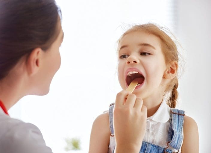 Doctor examining a child, checking her throat and tonsils