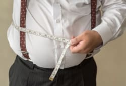 Overweight man holding a measuring tape