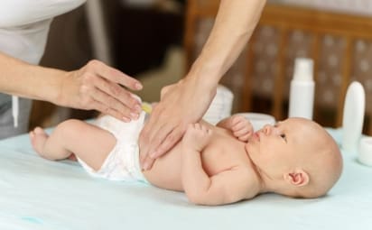 A mom changes her newborn baby's diaper on baby changing table.