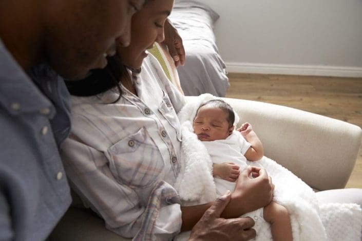 A new mother sitting down while holding her baby in her arms