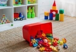 Children's playroom with plastic colorful educational blocks, toys, and games spilling out of a bin onto the floor.