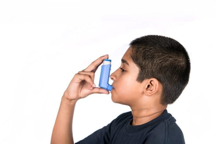 Young boy using asthma inhaler