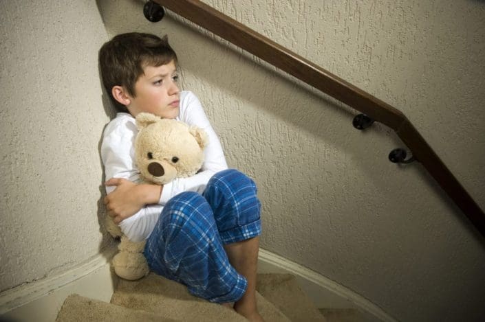Fearful boy hugging teddy bear