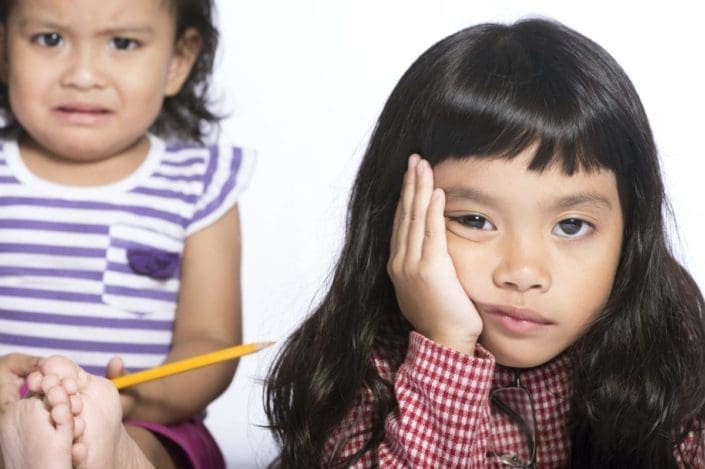 Younger sister looks sad while older sister looks frustrated