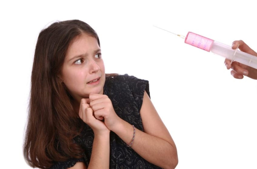 Scared girl looking at a big needle