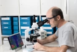 Male scientist or tech observes biopsy sample under a microscope